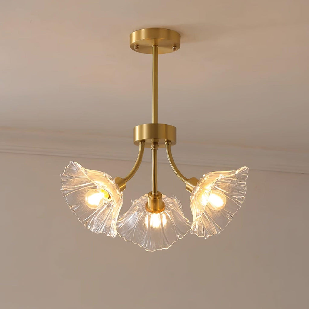 Warm light glows from this Clérachic chandelier's glass petal shades, hung in the corner of a softly lit room.