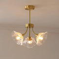Warm light glows from this Clérachic chandelier's glass petal shades, hung in the corner of a softly lit room.