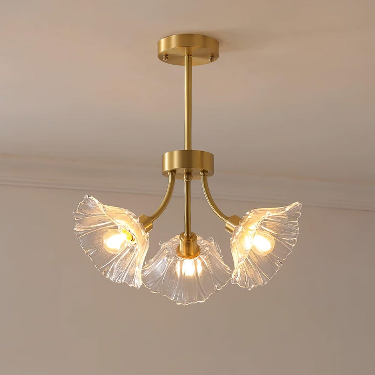 Warm light glows from this Clérachic chandelier's glass petal shades, hung in the corner of a softly lit room.