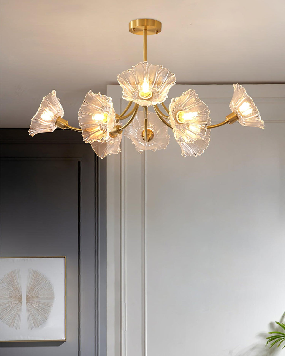Another angle against grey walls shows this Clérachic chandelier's brass frame with its glass petal shades spread wide.