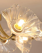 Close view of several ruffled glass petal shades fanning from the brass frame of this Clérachic chandelier, lit warmly.