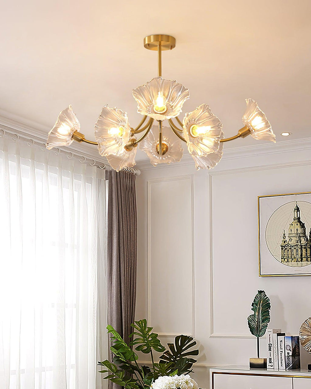 A window dressed in sheer curtains and a potted plant on a console table sit beneath this Clérachic chandelier.