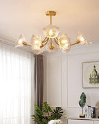 A window dressed in sheer curtains and a potted plant on a console table sit beneath this Clérachic chandelier.