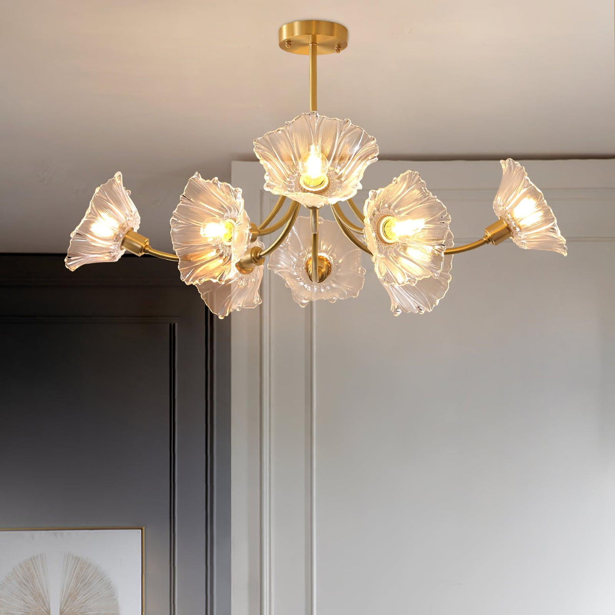 A side angle against plain grey walls shows this Clérachic chandelier's brass arms fanning out with clear glass petal shades.
