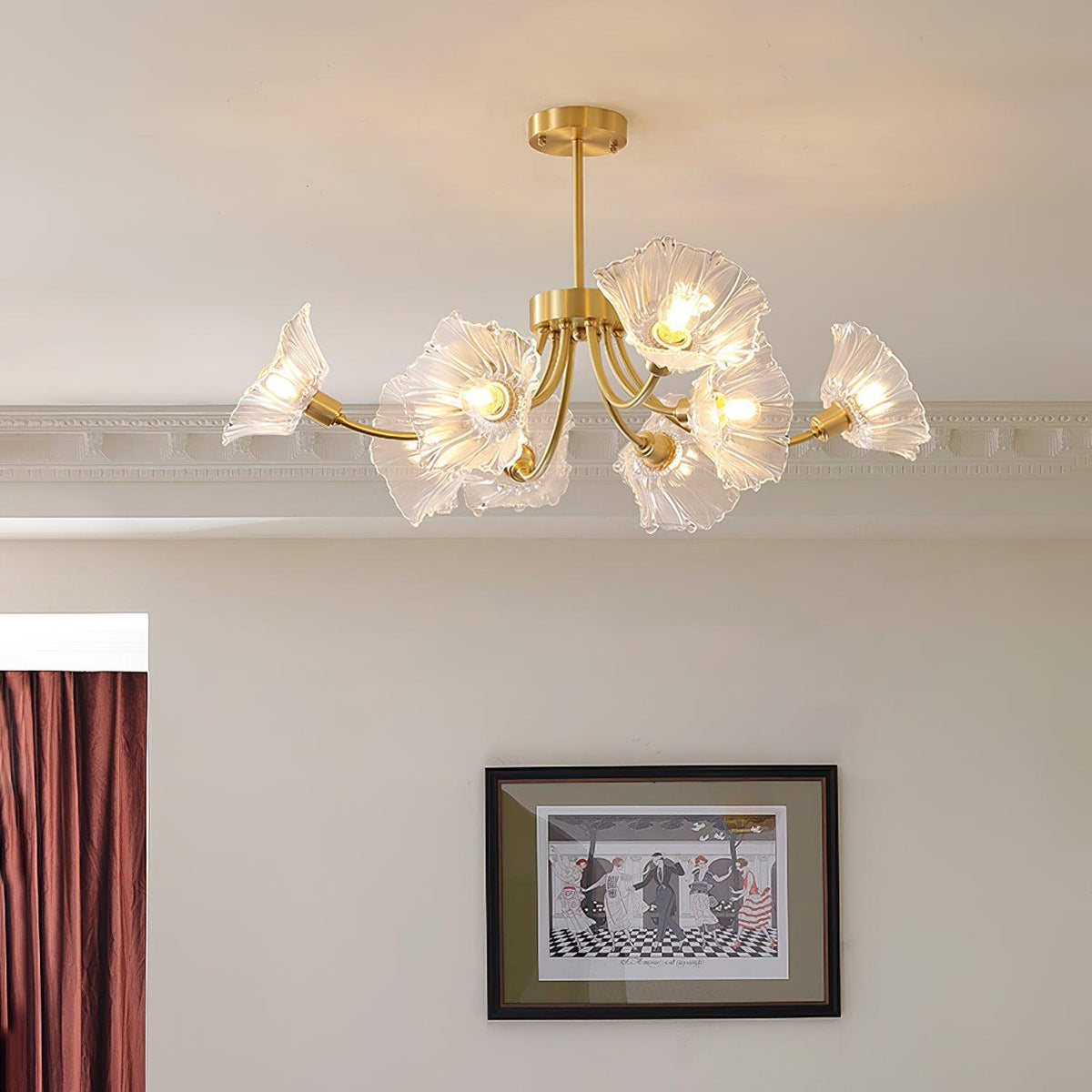 The brass frame and glass petal shades of this Clérachic chandelier hang near a framed artwork and a red curtain panel.