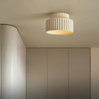 Pleated resin ceiling light glowing softly against a ceiling