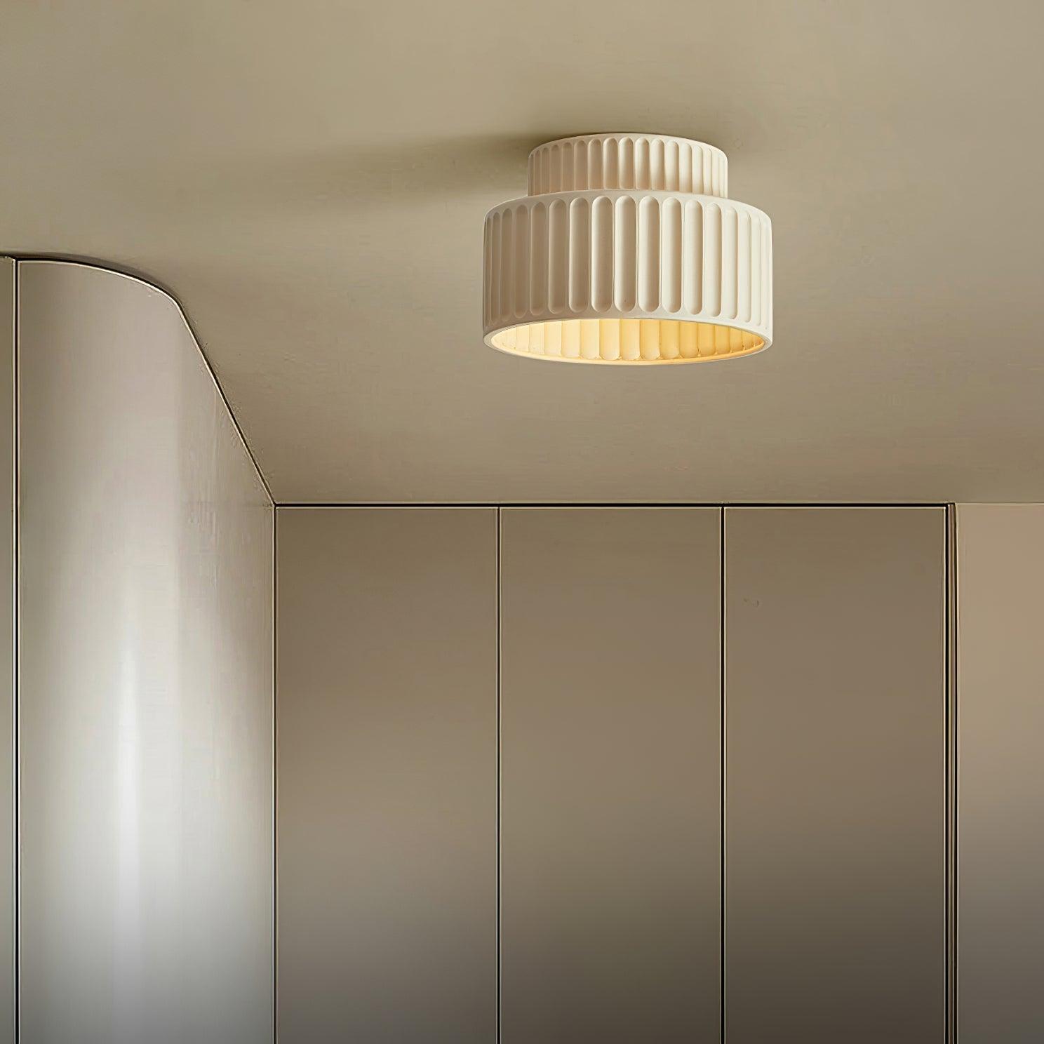 Pleated resin ceiling light glowing softly against a ceiling
