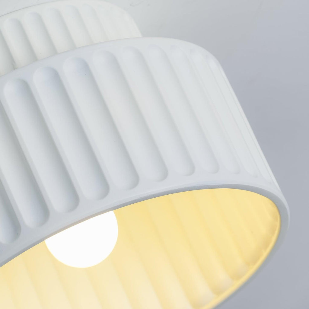 Pleated resin ceiling light glowing softly against a wall