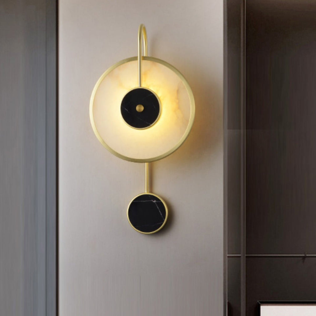 The fixture lit on a brushed metallic wall panel, black stone centre catching the glow.