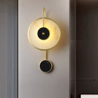 The fixture lit on a brushed metallic wall panel, black stone centre catching the glow.