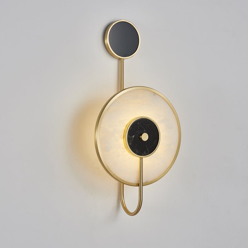 Modern wall sconce with gold frame and black circular accents on a light gray background