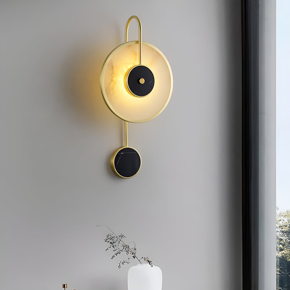 Lit on a grey wall beside a window, a white vase of dried stems on the sill below.