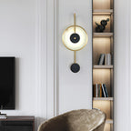 Lit in a living room beside a lit bookshelf, a velvet armchair below and a television left.
