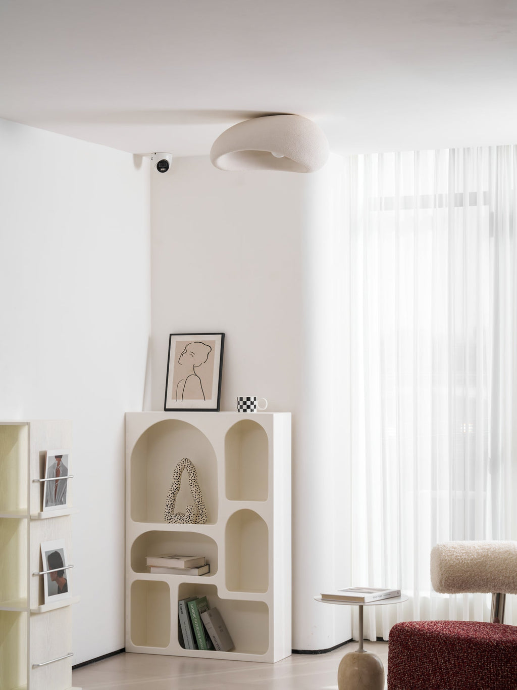 Near a sheer curtain, this Clérachic ceiling light glows above a shelving unit with a framed line drawing.