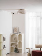 Near a sheer curtain, this Clérachic ceiling light glows above a shelving unit with a framed line drawing.