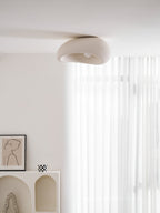 This Clérachic ceiling light glows above a framed line drawing and a chequered mug, sheer curtain behind.