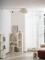 This Clérachic ceiling light lights a corner with a curved bookshelf, sheer curtains and a red ottoman.