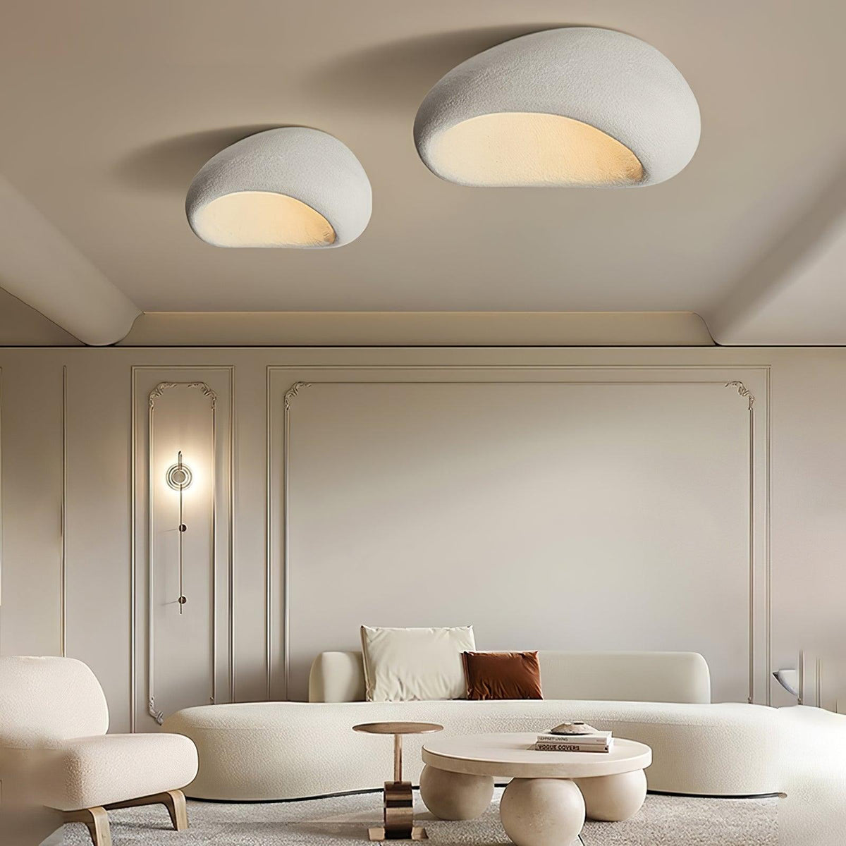Two sizes of this Clérachic ceiling light glow above a curved white sofa and round coffee table.