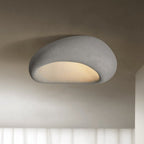 In a cement-grey finish, this Clérachic ceiling light glows against a shadowed studio backdrop.