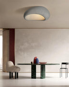 Above a dining table with a green marble base and red curtain, this Clérachic ceiling light glows in a pale finish.