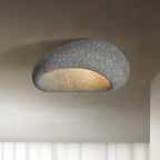 A dark speckled stone finish glows on this Clérachic ceiling light, set against a shadowed studio backdrop.