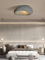 In a dark speckled finish, this Clérachic ceiling light glows above a bedroom with a slatted wood headboard wall.