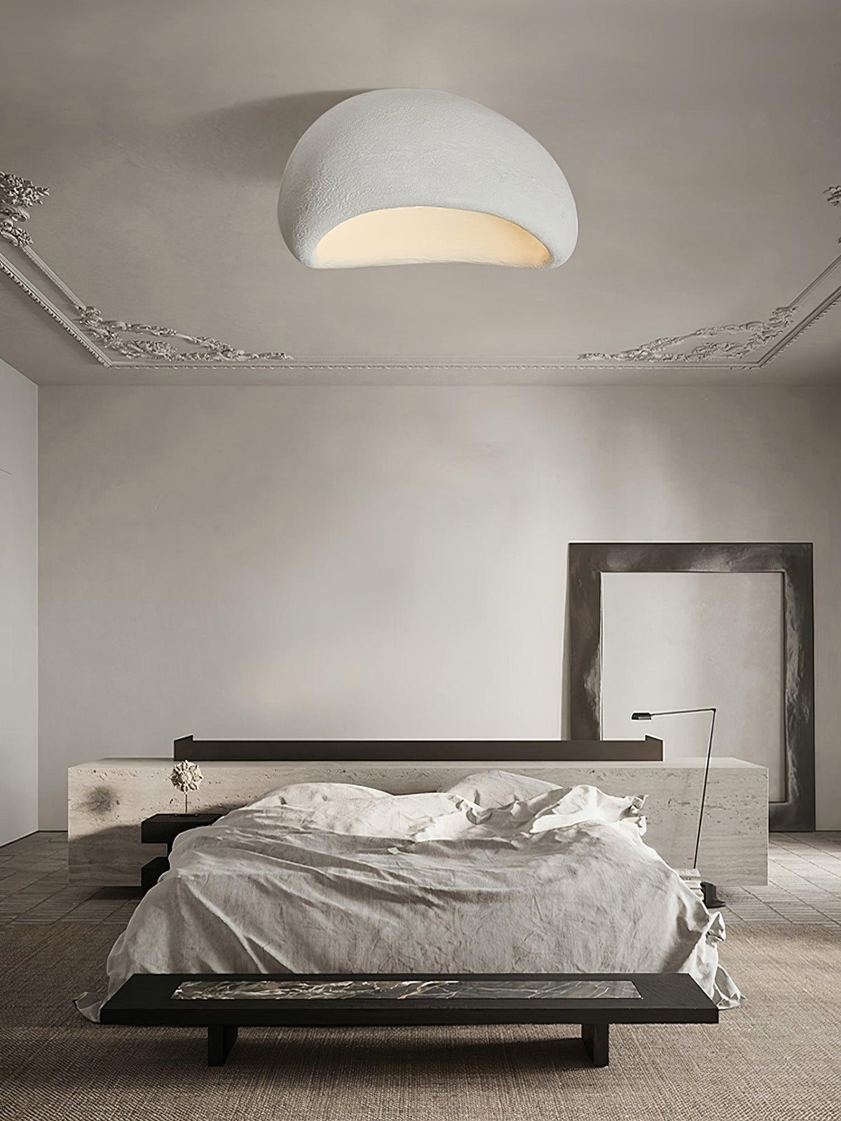 Beneath ornate cornice moulding, this Clérachic ceiling light glows in a pale finish above a dark bench and bed.