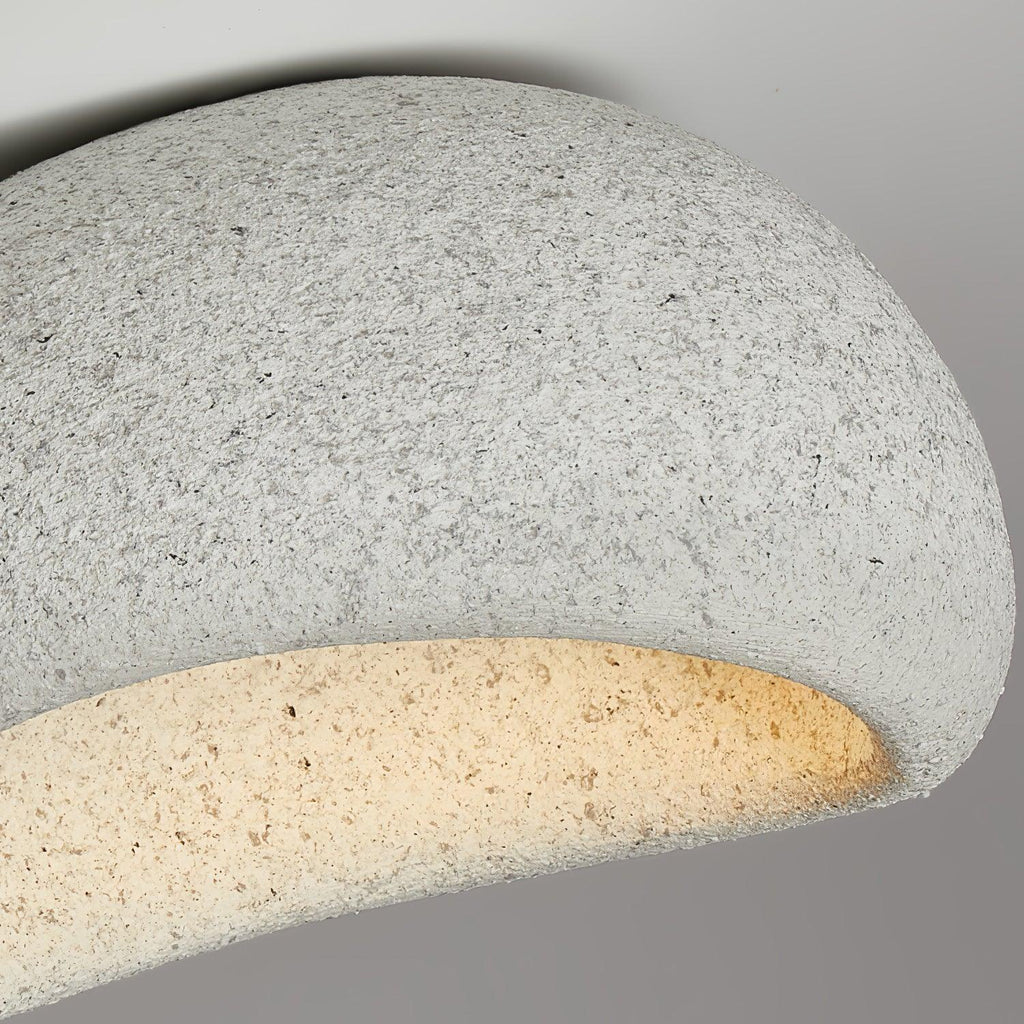 Extreme close-up of the granite-like texture on this Clérachic ceiling light, its underside glowing warmly.