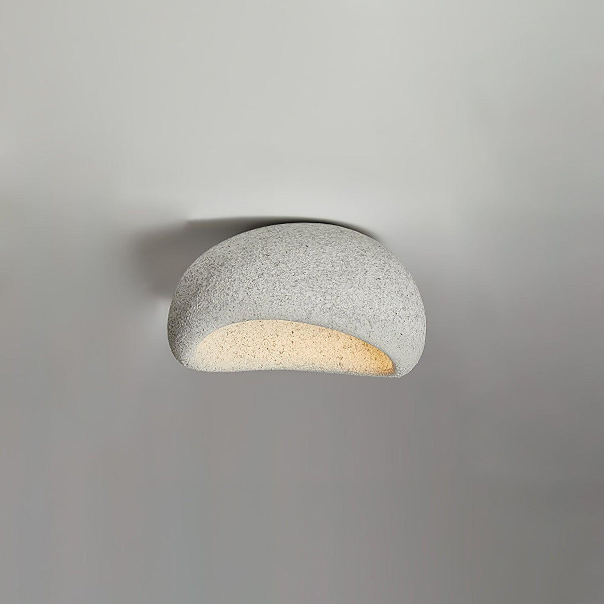 A small size of this Clérachic ceiling light in a light speckled finish glows against plain grey.