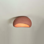 In brick red, this Clérachic ceiling light glows against a softly lit grey background.