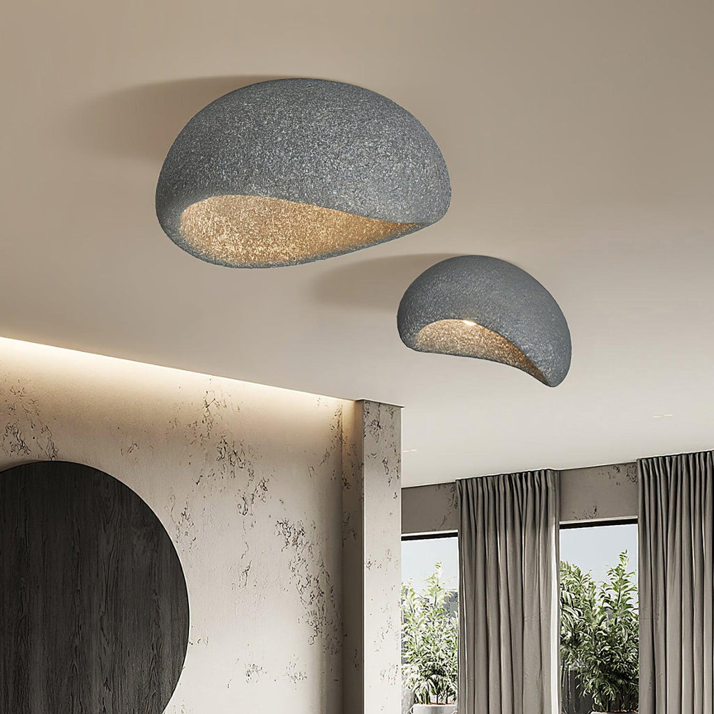 A large and small pair of this Clérachic ceiling light lights a room with a curved stone wall and garden view.