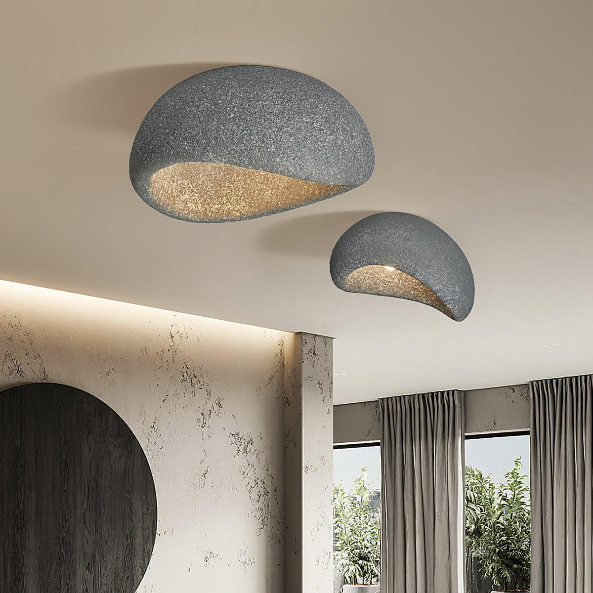 A large and small pair of this Clérachic ceiling light lights a room with a curved stone wall and garden view.