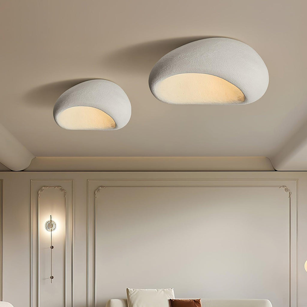 Two sizes of this Clérachic ceiling light glow above a panelled wall, a sofa just visible below.