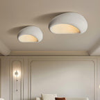 Two sizes of this Clérachic ceiling light glow above a panelled wall, a sofa just visible below.