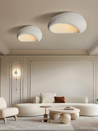 Two sizes of this Clérachic ceiling light glow above a panelled living room with a wall sconce and curved sofa.