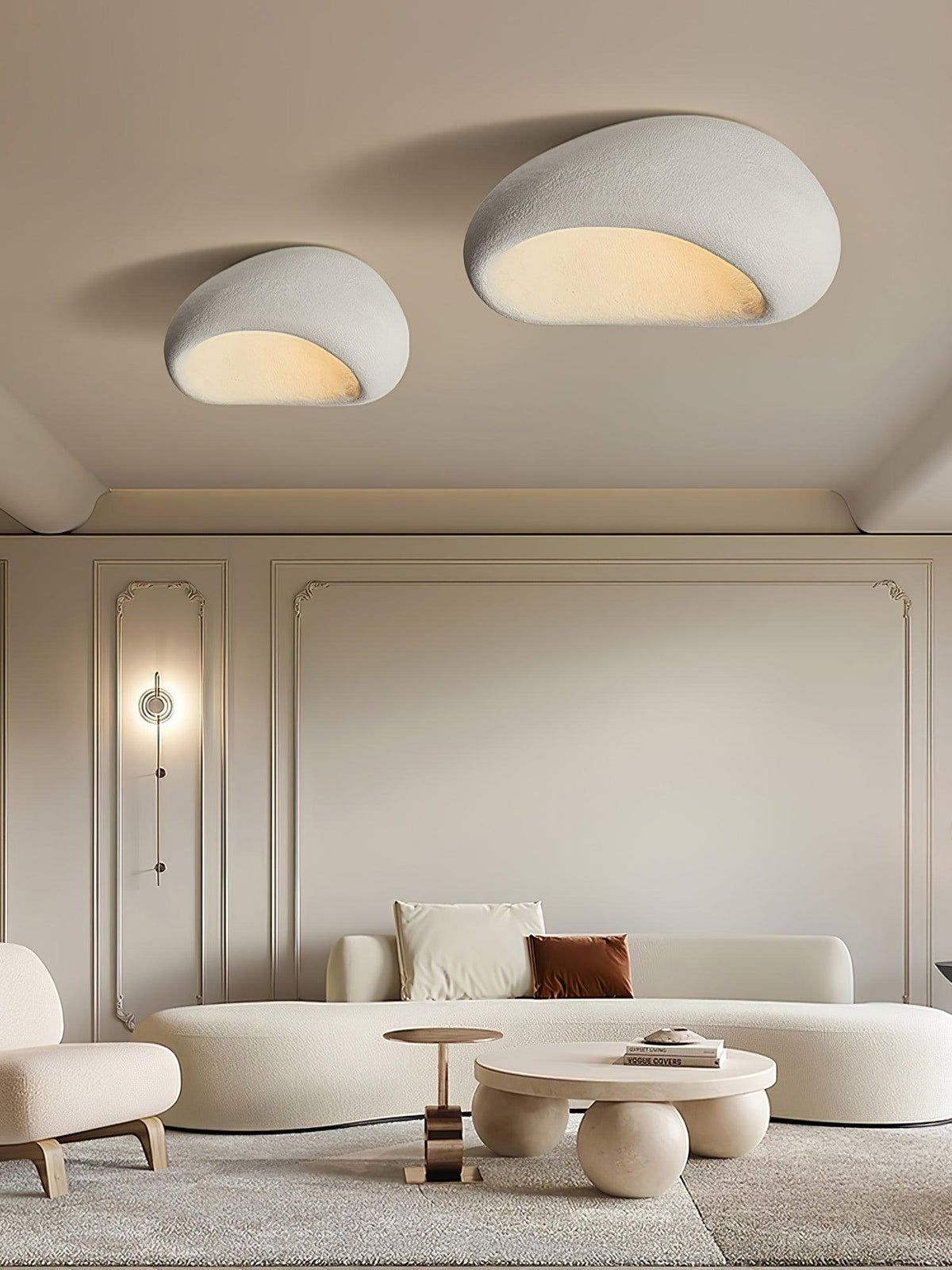 Two sizes of this Clérachic ceiling light glow above a panelled living room with a wall sconce and curved sofa.