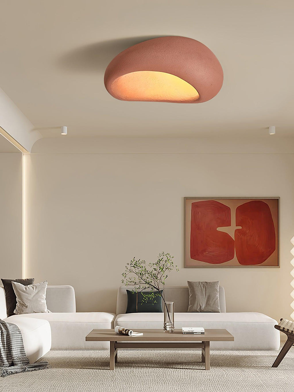 In brick red, this Clérachic ceiling light glows above a living room with a red abstract art print and a plant.