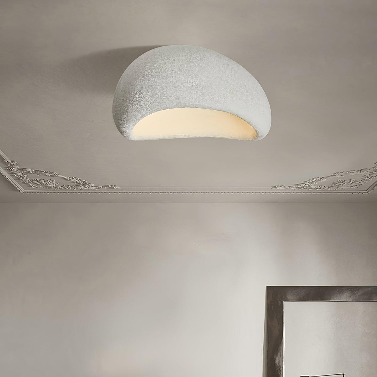 Beneath a decorative cornice, this Clérachic ceiling light glows in white texture, a mirror frame leaning against the wall.