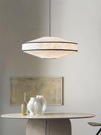 Close view of this Clérachic pendant's black-trimmed paper shade glowing above a round table with glass vases and framed art.
