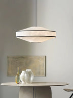 Glass vases and a framed abstract print sit on a round table below this glowing Clérachic pendant.