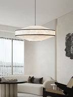 Sheer vertical blinds and a rattan chair furnish the living room where this Clérachic pendant glows overhead.