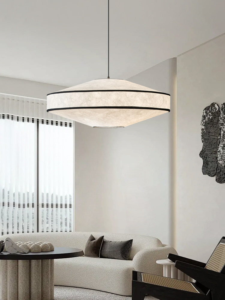 Sheer vertical blinds and a rattan chair furnish the living room where this Clérachic pendant glows overhead.