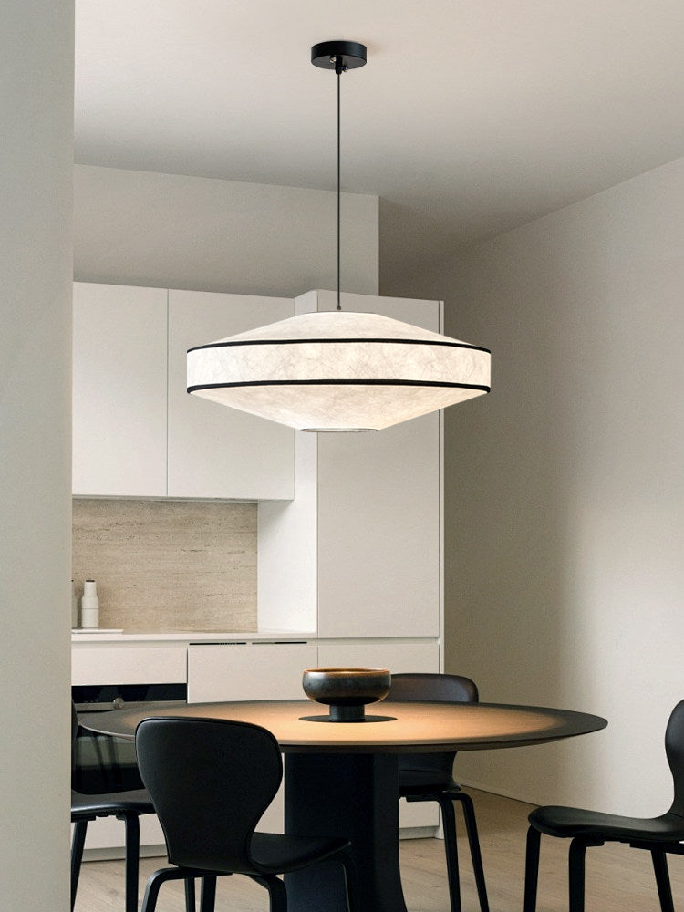 White cabinetry and black dining chairs frame the kitchen table this glowing Clérachic pendant hangs above.