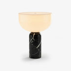Clérachic touch-control table lamp with a warm white dome shade rising from a polished black marble cylinder, shown on a plain studio backdrop.
