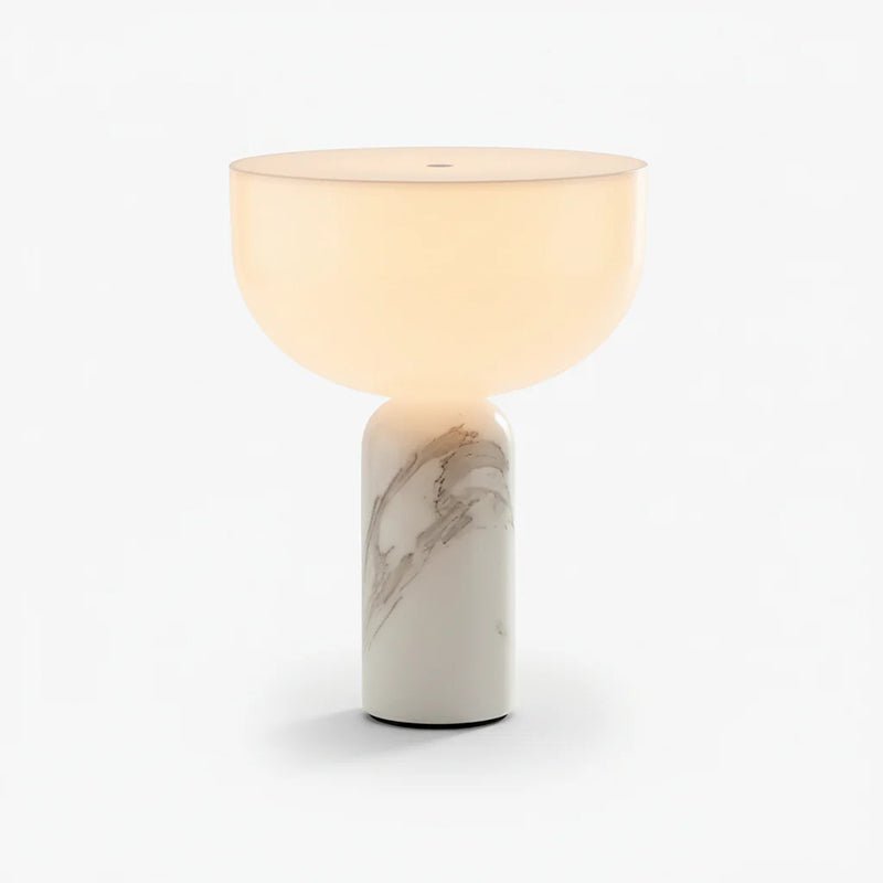 This Clérachic sphere table lamp in pale cream marble, lit and photographed against a plain light grey background.
