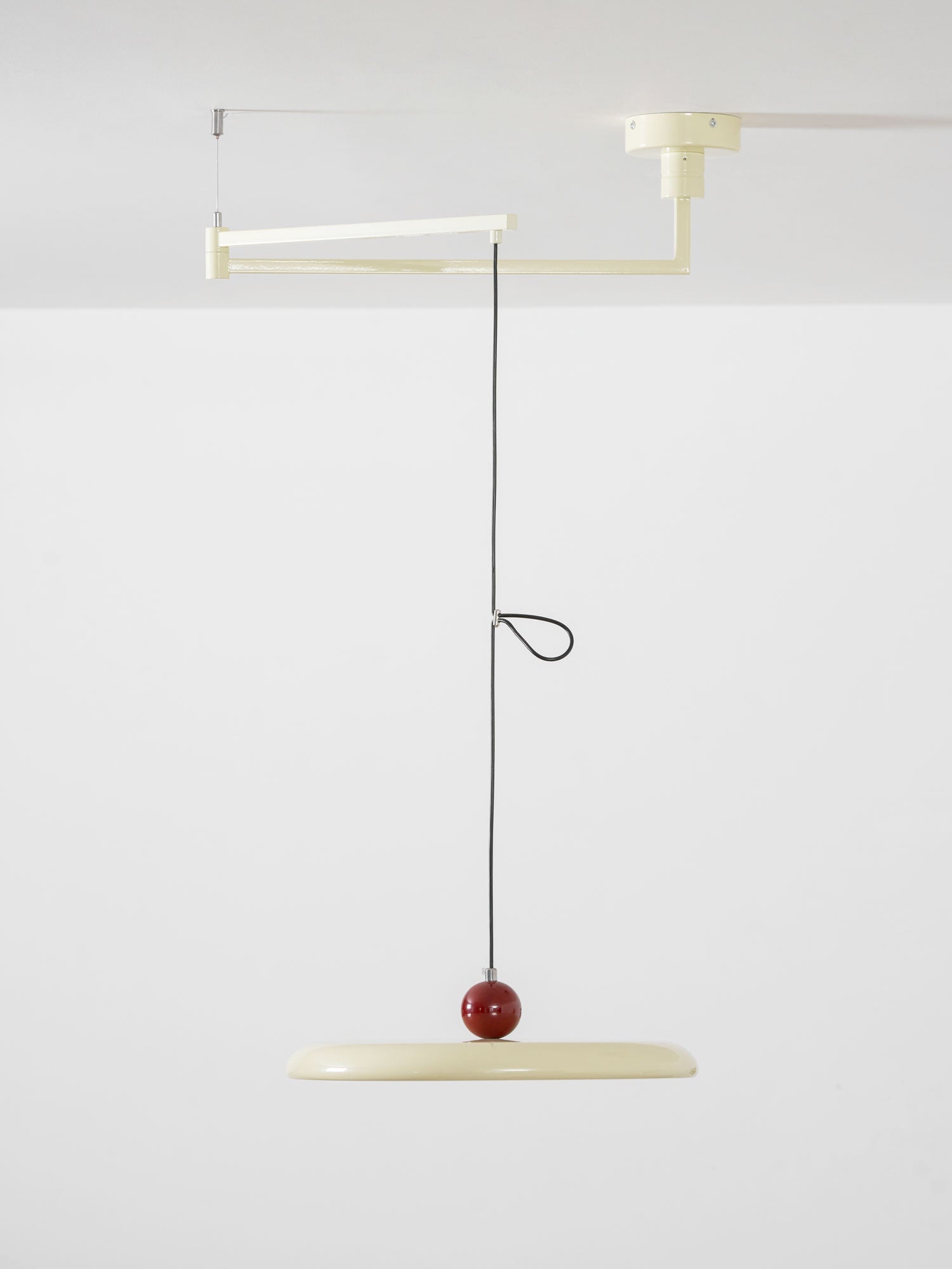 Swing arm pendant light with slim lit disc over a studio desk