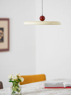 Dark red swing arm pendant light glowing over a table