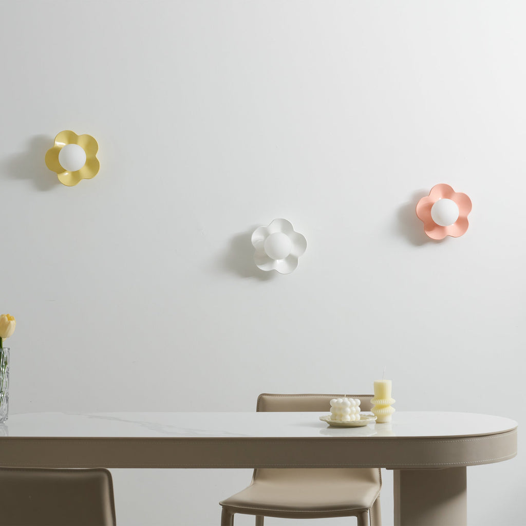 Three of these Clérachic wall lights are mounted above a dining table, in yellow, white and pink, all unlit.