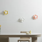 Three of these Clérachic wall lights are mounted above a dining table, in yellow, white and pink, all unlit.