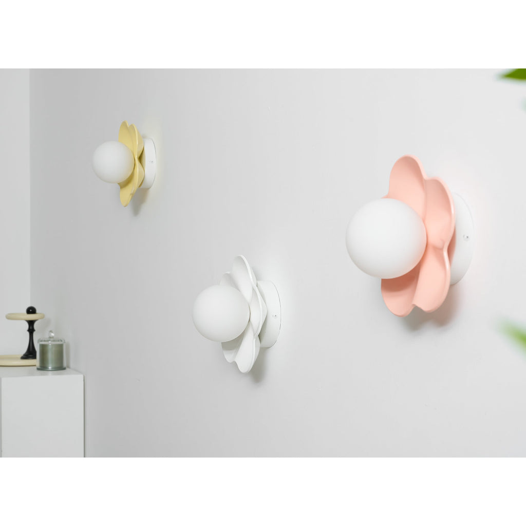 Three of these Clérachic wall lights are mounted together, in yellow, white and pink, the pink one closest and lit.